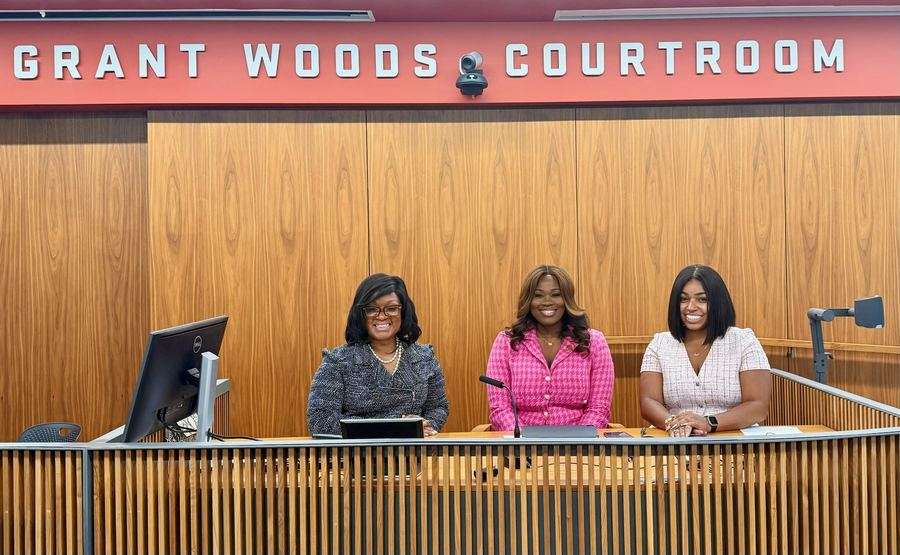Rosiland Moore seated on a judging panel with two other panelists at the Grant Woods Courtroom